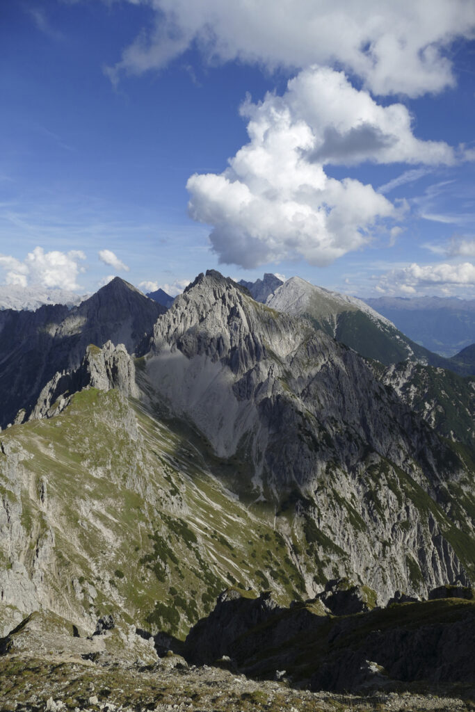 Alpines Bergpanorama mit felsigen Gipfeln und grünen Berghängen in der Region Absam in Tirol unter blauem Himmel mit weißen Wolken