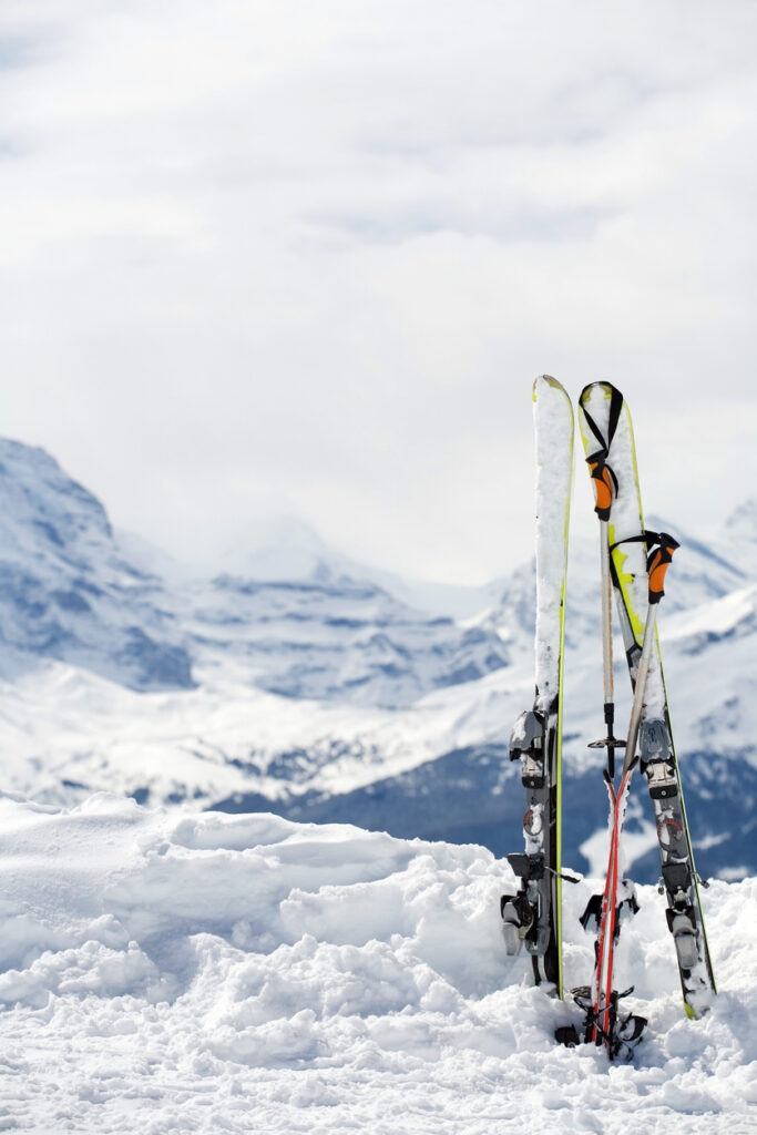 Zwei Paar Ski und Skistöcke stecken im Schnee vor verschneiter Bergkulisse in Volders