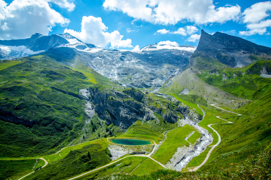 Idyllischer Bergsee umgeben von grünen Almwiesen und schneebedeckten Gletschergipfeln in der Bergregion Tux